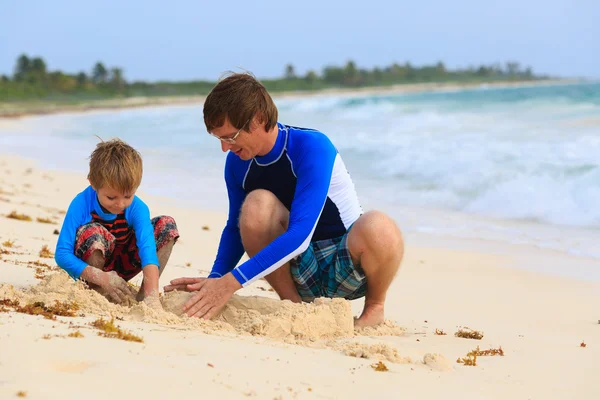 Vader en zoon gebouw sandcastle op het strand — Stockfoto