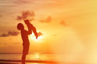 Baba ve kızı siluetleri batımında sahilde