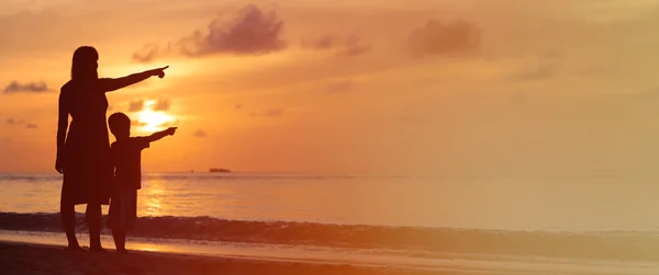 Mutter und Sohn am Strand bei Sonnenuntergang und zeigen auf die Sonne — Stockfoto