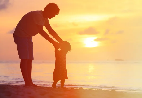 Silhouetten van vader en dochtertje lopen bij zonsondergang — Stockfoto