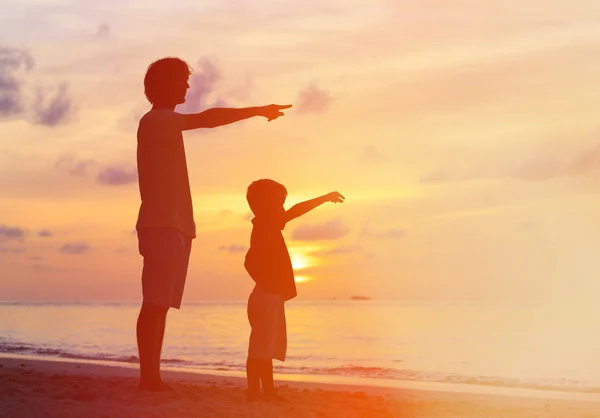 Vader en zoon op sunset beach, wijzend naar de zon — Stockfoto