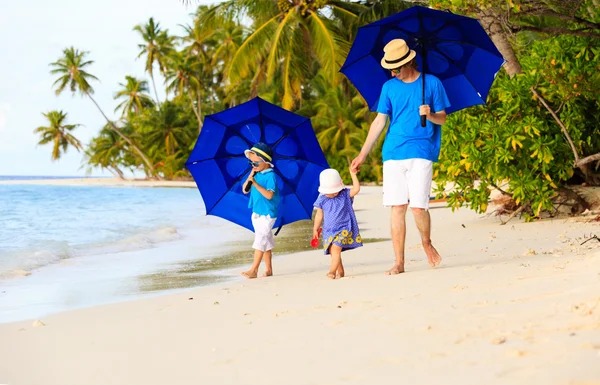 Vader en kinderen op het strand met parasols te verbergen van zon — Stockfoto