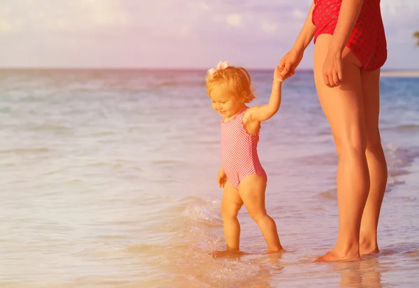 Mère et petite fille marchant sur la plage du coucher du soleil — Photo