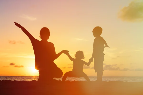 Vader met kinderen silhouetten plezier bij zonsondergang — Stockfoto