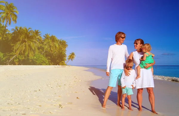 Familia joven con dos niños caminando en la playa —  Fotos de Stock