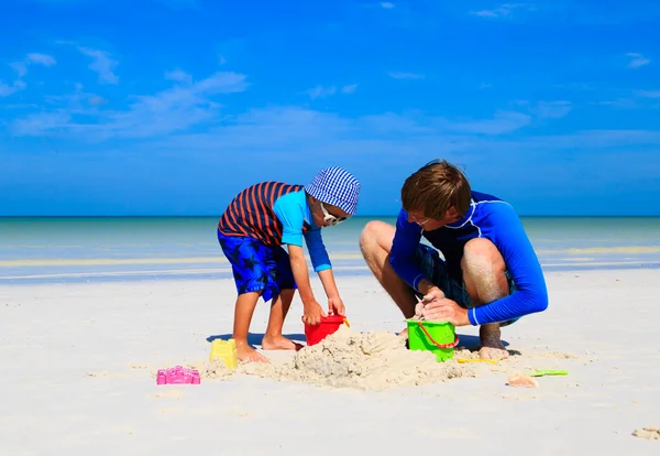 Padre e figlio costruzione castello di sabbia sulla spiaggia tropicale — Foto Stock