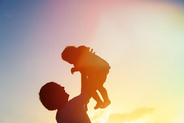 Pai e pequena filha silhuetas ao pôr do sol — Fotografia de Stock