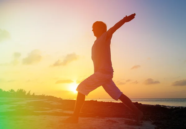 Silhouette of young man doing yoga at sunset — Stock Photo, Image