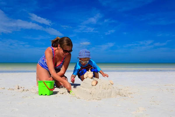 mother and son building sand castle on tropical beach