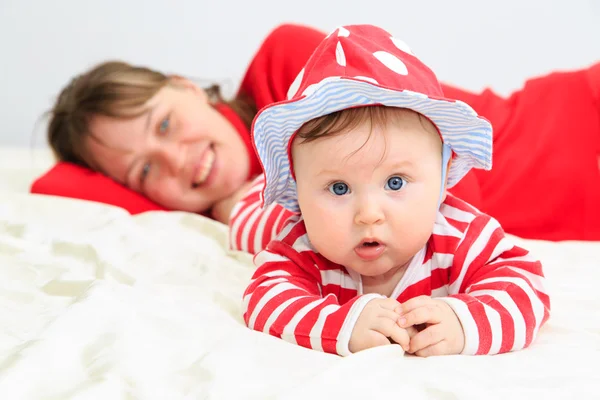Porträtt av söt liten baby flicka i röd hatt med mamma — Stockfoto