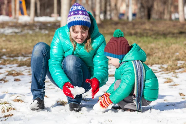 Mother and son building snowman in winter — Stock Photo, Image