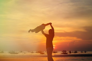 Baba ve oğul siluetleri günbatımında oynamak