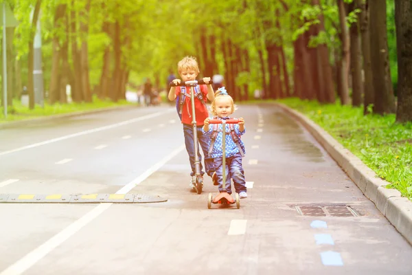 Маленький хлопчик і дівчинка катаються на скутерах у місті — стокове фото