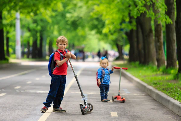 Kisfiú és a lány lovaglás a robogó a városban — Stock Fotó