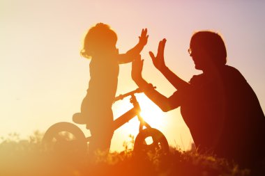 Baba ve kızı gün batımında bisiklet sürerken eğleniyorlar.