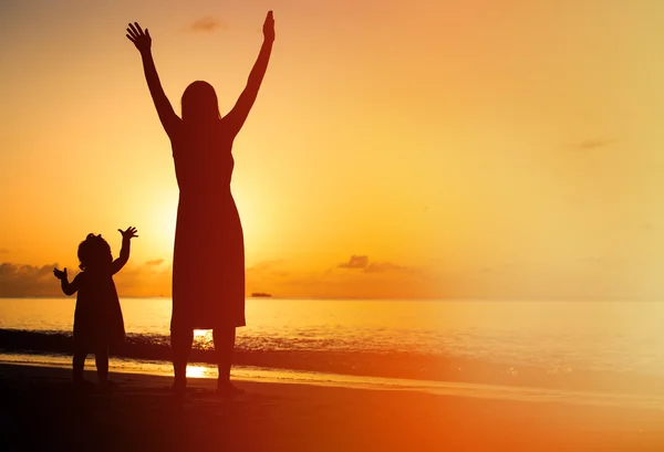 母亲和小女儿举起手来在海滩的剪影 — 图库照片