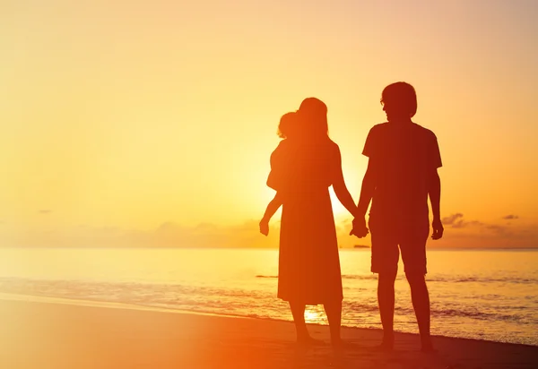 Romantisch paar met kindje op zonsondergang tropisch strand — Stockfoto