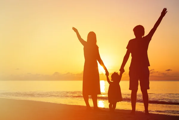 Familia feliz con el niño divirtiéndose en la playa puesta del sol — Foto de Stock