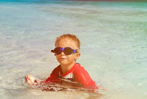 Bambino nuoto tenuta shell sulla spiaggia — Foto Stock