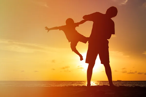 Silhouettes de père et fils s'amuser au coucher du soleil — Photo