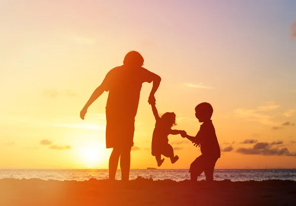 Vader met kinderen silhouetten plezier bij zonsondergang — Stockfoto