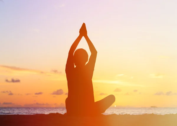 Silhouette of young man doing yoga at sunset — Stock Photo, Image