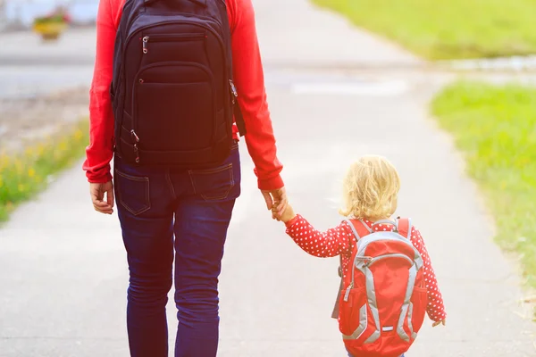 Mãe segurando a mão de pequena filha com mochila ao ar livre — Fotografia de Stock