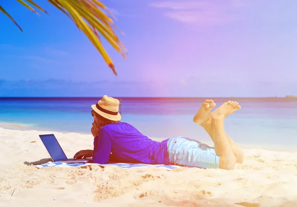 Молодий чоловік з ноутбуком на тропічному пляжі — стокове фото