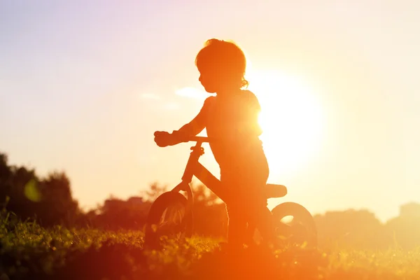 Menina equitação bicicleta no por do sol — Fotografia de Stock