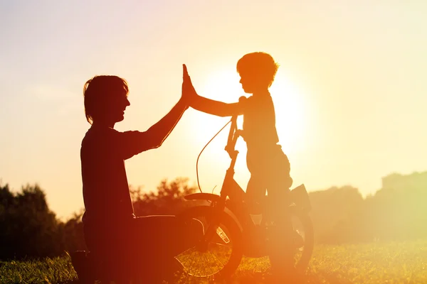Pai e filho se divertindo andando de bicicleta ao pôr do sol — Fotografia de Stock
