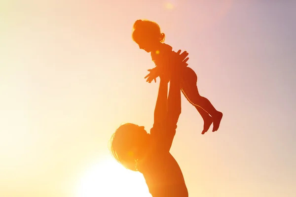 Silhuetas de pai e filha brincando ao pôr do sol — Fotografia de Stock