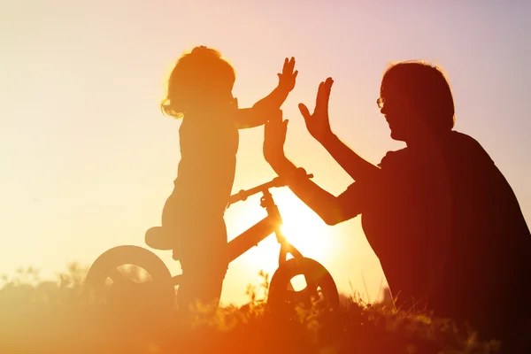 Ojciec i córka dobrze się bawią na rowerze o zachodzie słońca — Zdjęcie stockowe