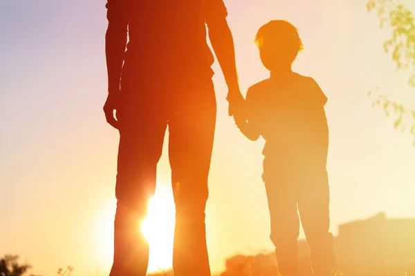 Sziluett apa és fia fogja egymás kezét naplementekor — Stock Fotó
