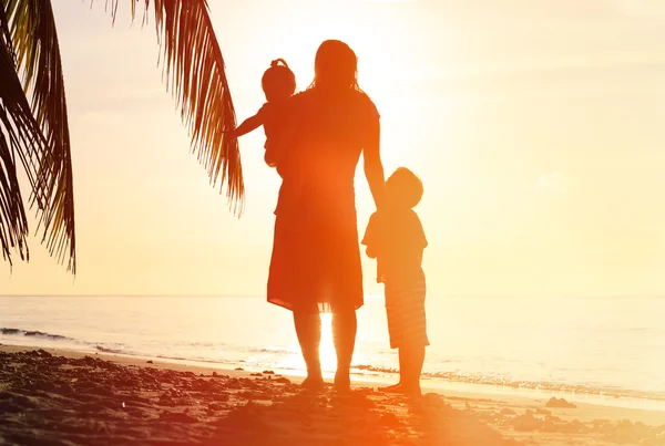 Madre y dos niños caminando en la playa al atardecer — Foto de Stock