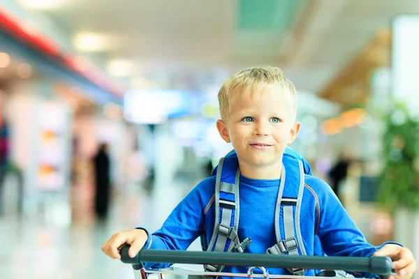 Felice bambino carino in aeroporto cavalcando sul carrello bagagli — Foto Stock