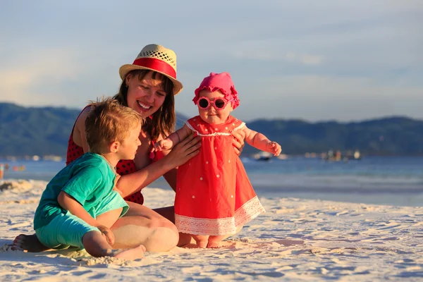 Madre e hijos divirtiéndose en la playa de arena — Foto de Stock