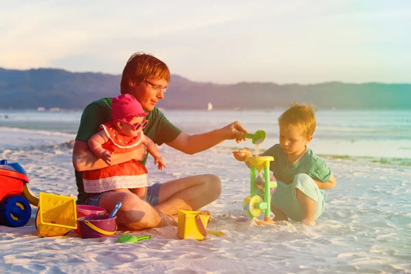 Vader met twee kinderen spelen op tropisch strand — Stockfoto