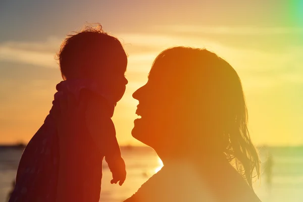 Mãe feliz e bebê na praia do por do sol — Fotografia de Stock