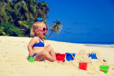 Tropikal plajda kumla oynayan tatlı küçük kız.