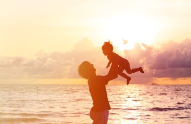 Baba ve küçük kızı siluetleri gün batımında