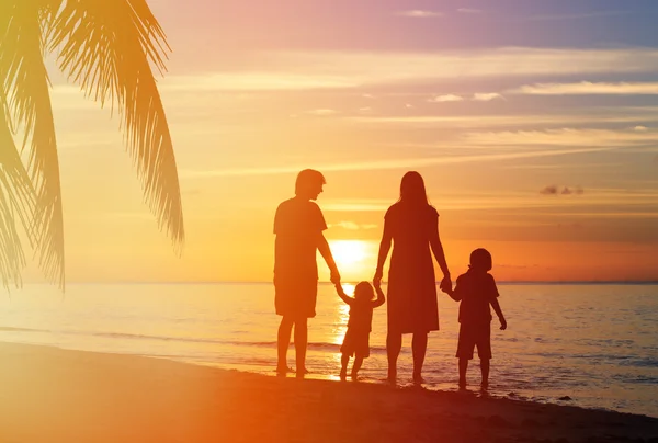 Familia feliz con dos niños divirtiéndose en la playa del atardecer — Foto de Stock