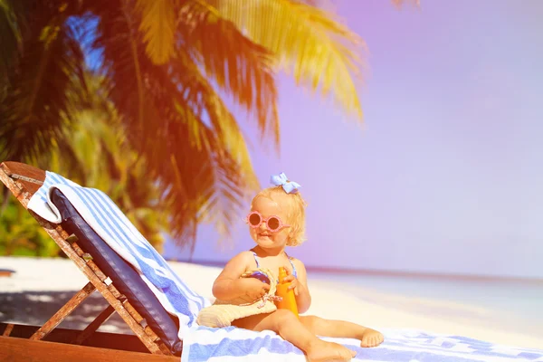 Menina bonito com creme protetor solar na praia — Fotografia de Stock