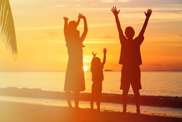 Família feliz com duas crianças se divertindo na praia do pôr do sol — Fotografia de Stock