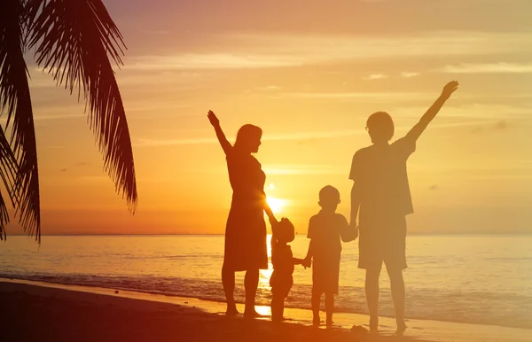 Família feliz com duas crianças se divertindo na praia do pôr do sol — Fotografia de Stock