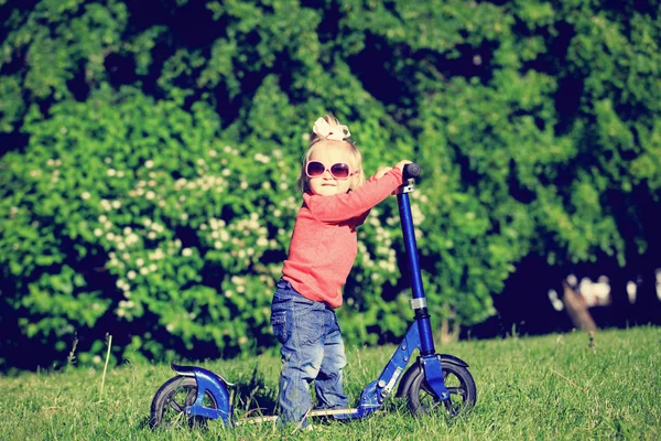 Bambina cavalcando scotter nel parco estivo — Foto Stock