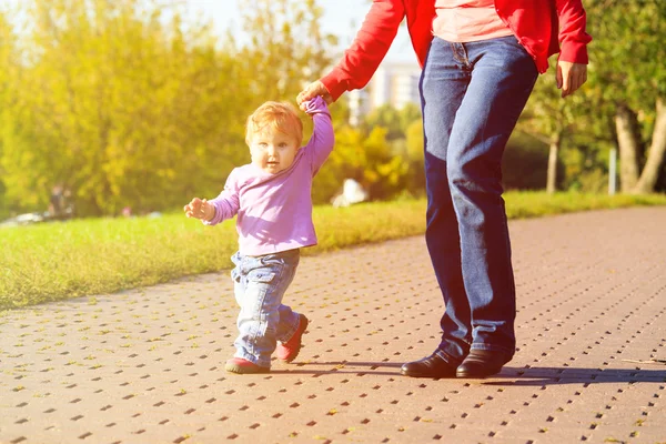 Madre e hija pequeña dando los primeros pasos en el parque — Foto de Stock