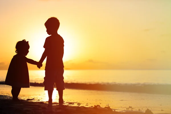 Petit garçon et fille tenant la main au coucher du soleil — Photo