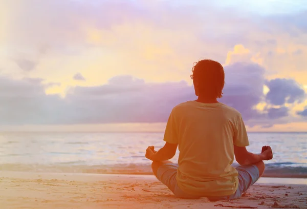 Gün batımında meditasyon genç adam silüeti
