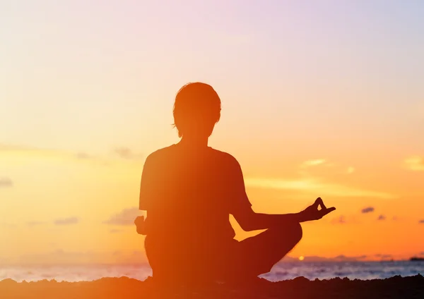 Silueta de joven meditando al atardecer — Foto de Stock