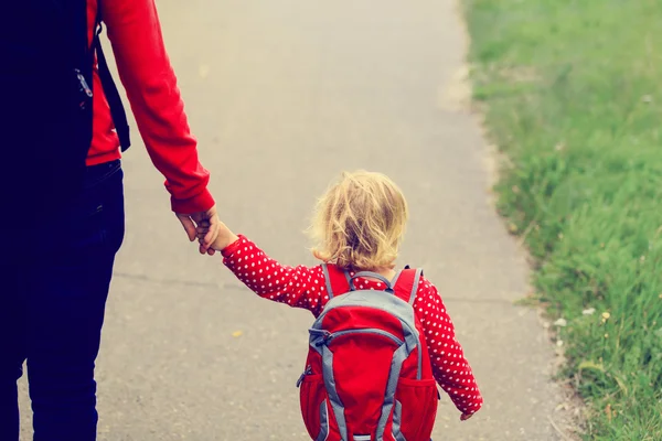 Mother holding hand of little daughter with backpack — Stock Photo, Image